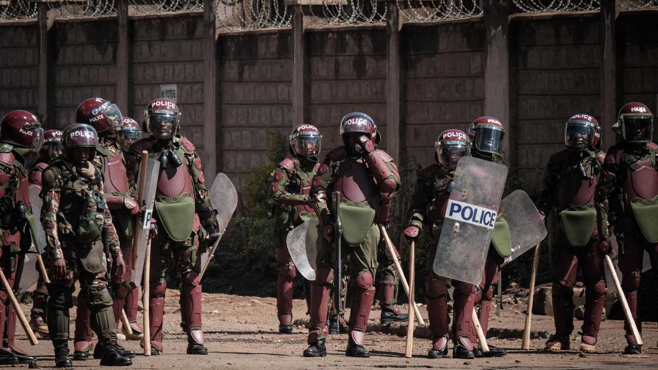Kenyan Police officers watch protesters as they block the street during a mass rally. Credit: AFP Photo