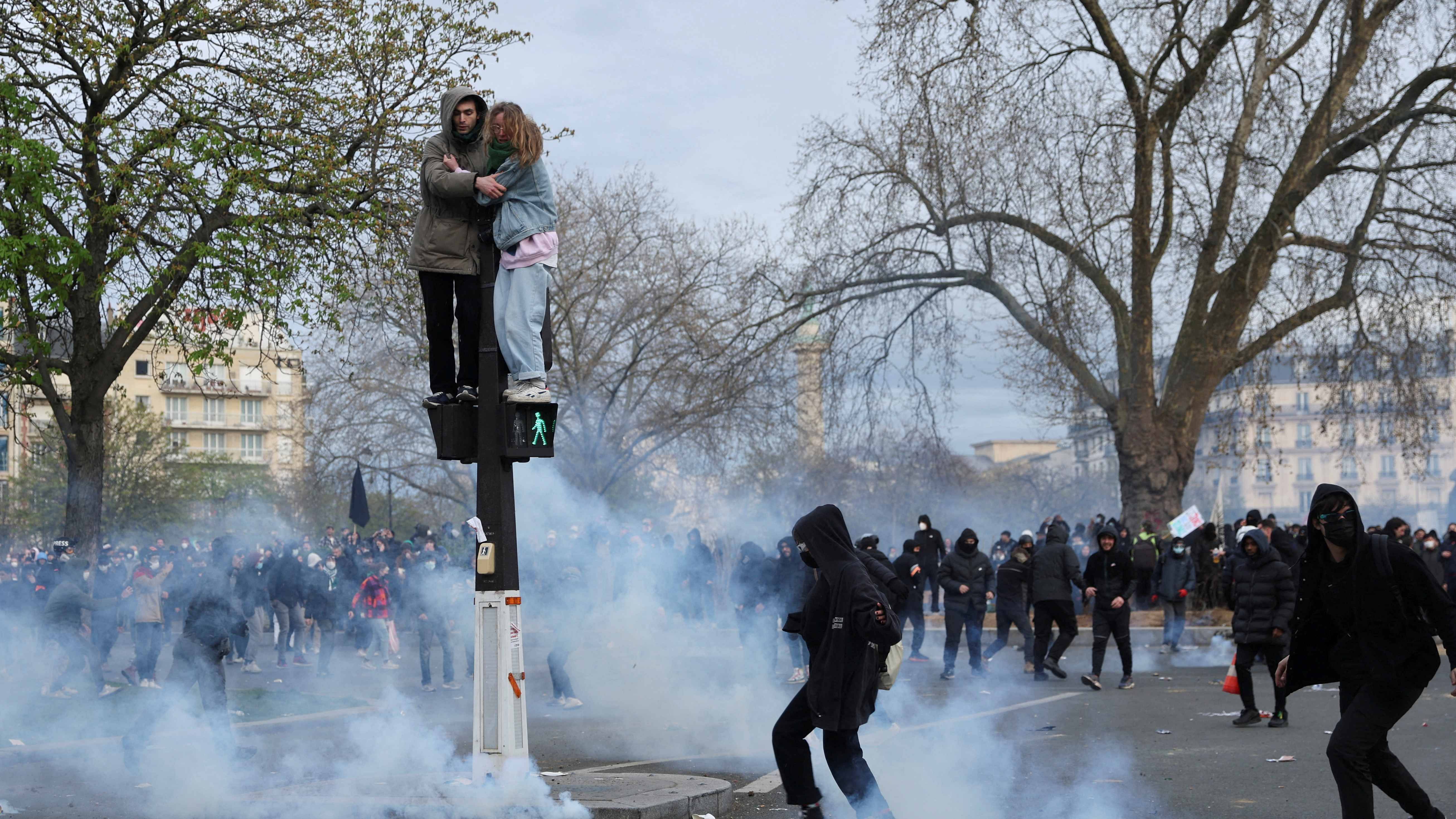 People stand on a pedestrian traffic light during clashes at a demonstration as part of the tenth day of nationwide strikes and protests against French government's pension reform in Paris, France, March 28, 2023. Credit: Reuters Photo