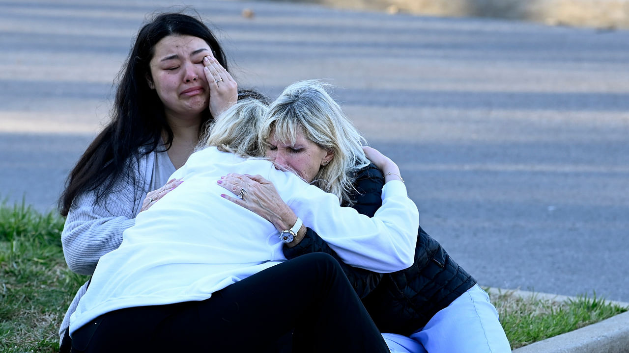 Former Covenant School students Ashley Crafton, top left, and Josephine Horn comfort their former six grade teacher, Lisa Horn, right, at a makeshift memorial by the entrance of the Covenant School. Credit: AP Photo