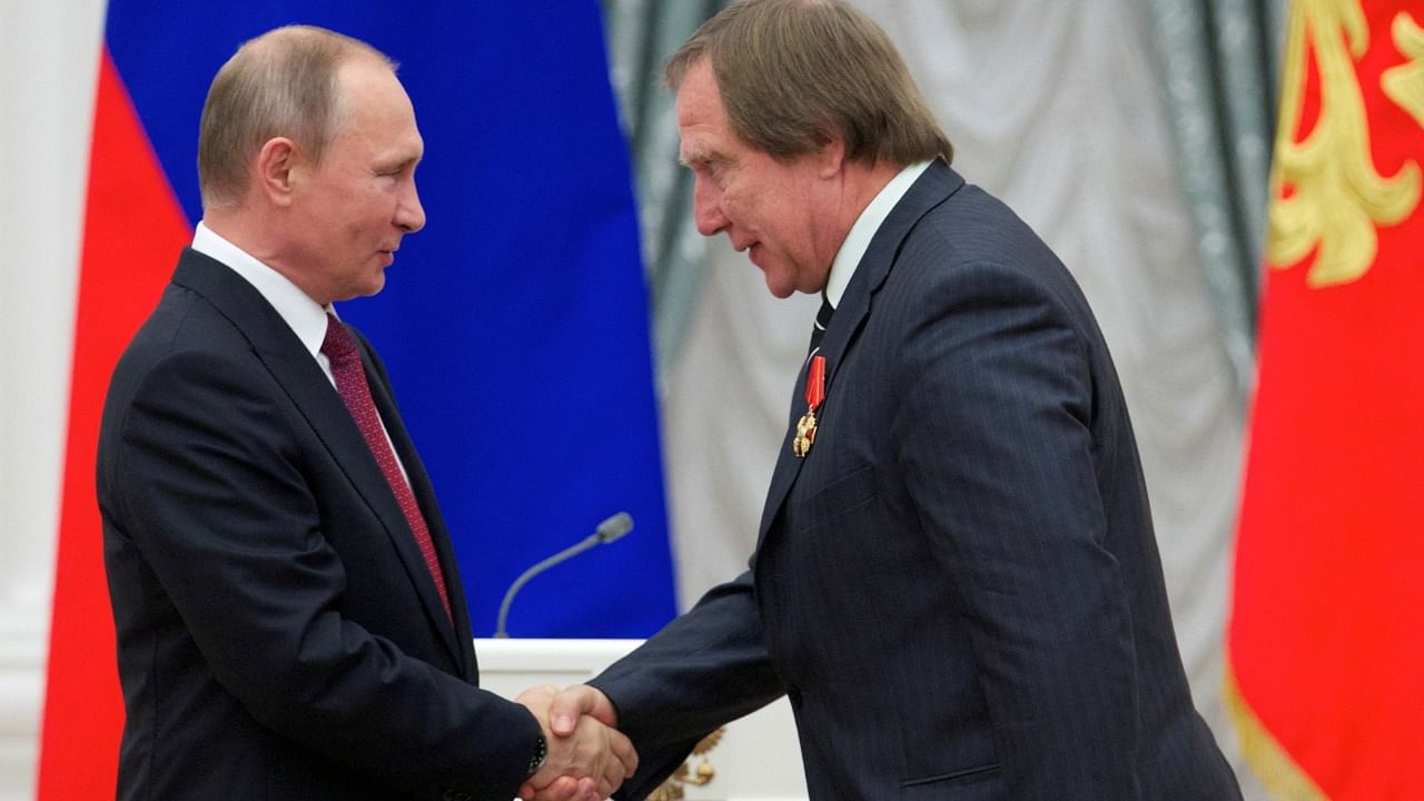 Russian President Putin shakes hands with artistic director of St. Petersburg House of Music Sergei Roldugin in Moscow in 2016. Credit: Reuters File Photo