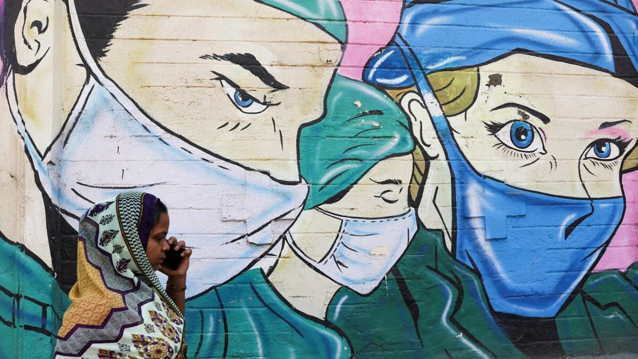 A woman walks past a coronavirus (COVID-19) themed mural on a street in Mumbai, India, March 28, 2023. Credit: Reuters Photo