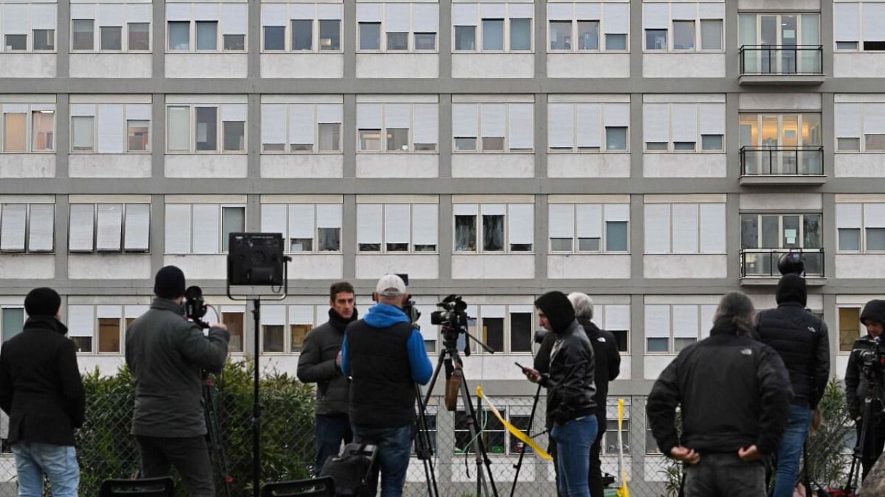 Television journalists report live from a small hill overlooking the Gemelli hospital on March 30, 2023 in Rome, where Pope Francis was admitted on March 29. Credit: AFP Photo