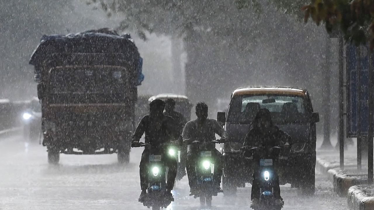 Commuters make their way along a road amid rainfall in New Delhi. Credit: AFP Photo