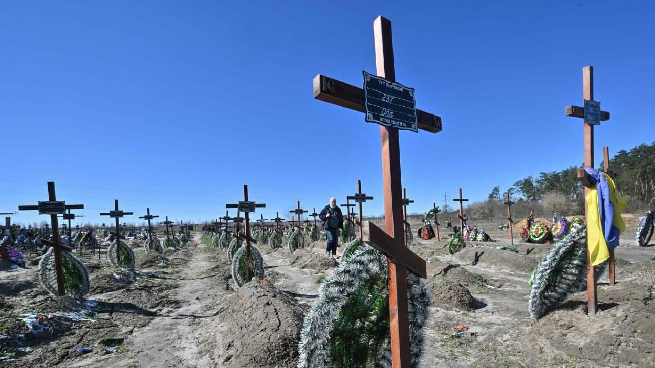 A man walks among graves of unidentified local people who were killled in the Ukrainian town of Bucha, northwest of Kyiv on March 30, 2023, a day before the celebration of the first anniversary of the Bucha liberation from Russian troops on March 31. Credit: AFP Photo