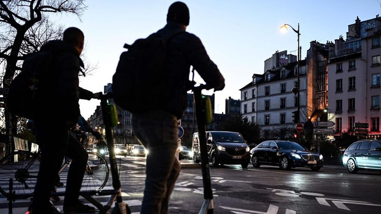 People wait on free-float electric scooters as vehicles drive down a boulevard in central Paris. Credit: AFP Photo