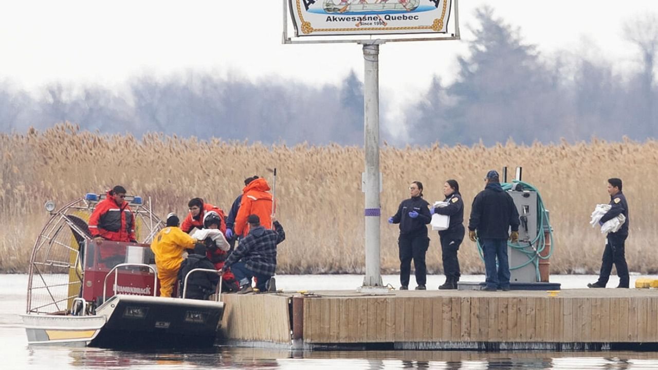 Police and firemen carry a bag off their search boat from the marshland in Akwesasne, Quebec, Canada. Credit: Reuters Photo
