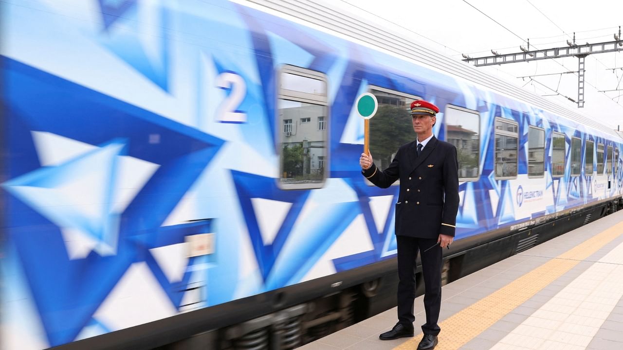 A station master shows a green sign to a train at the Athens central train station, as Greece resumes the train from Athens to Thessaloniki, on the same route of the deadly crash in Athens, Greece, April 3, 2023. Credit: Reuters Photo