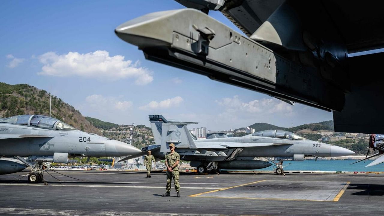 US Navy sailors stand guard near F/A-18F jets on the flight deck aboard tthe USS Nimitz (CVN-68) aircraft carrier during its port visit to Busan. Credit: AFP Photo