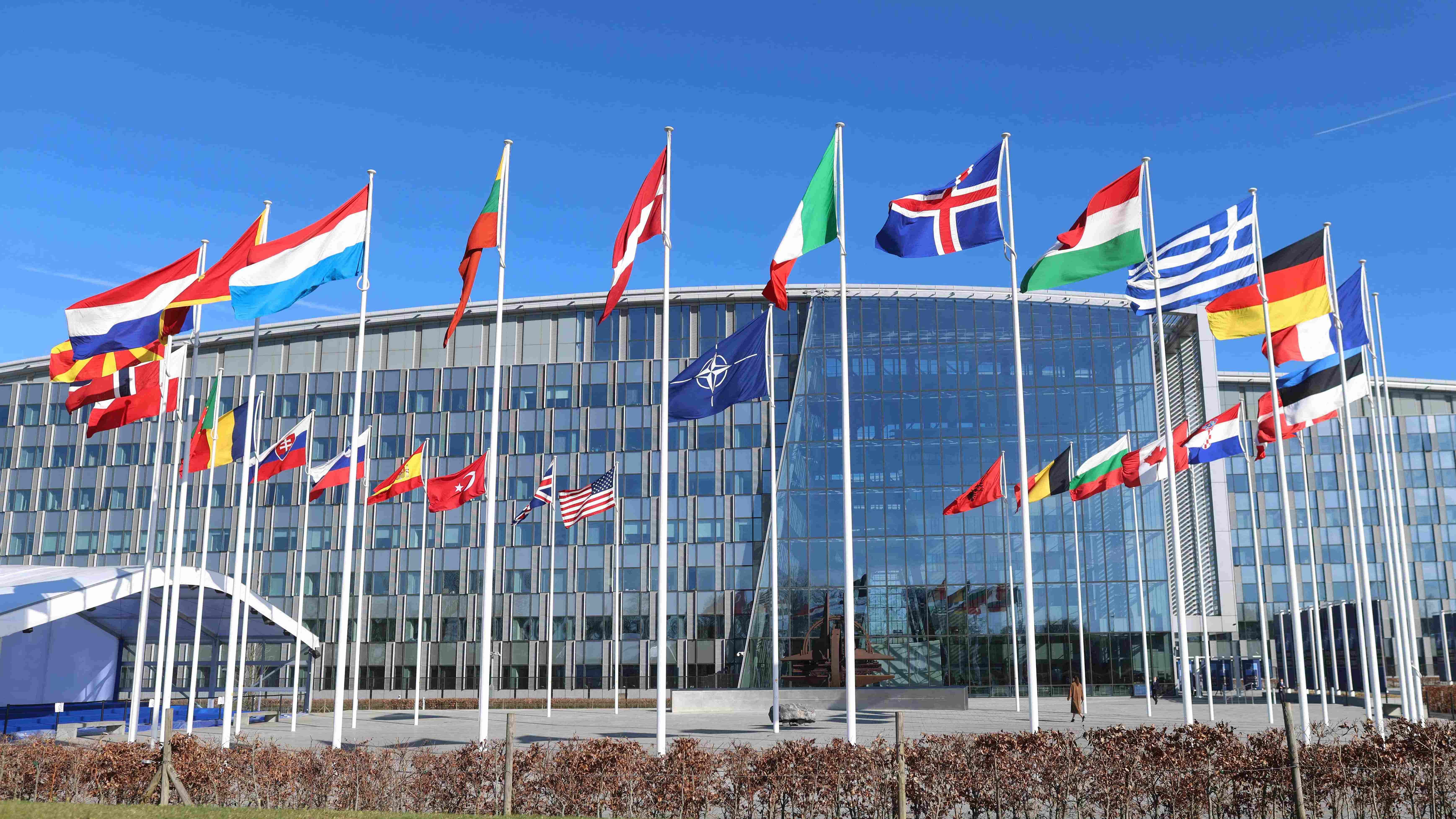 A photo shows member country flags with one empty mast ahead of a flag-raising ceremony for Finland's accession to NATO, in the Cour d'Honneur of the NATO headquarters in Brussels, on April 4, 2023. - Finland becomes the 31st member of NATO on April 4, in a historic strategic shift provoked by Moscow's war on Ukraine, which doubles the US-led alliance's border with Russia.  Credit: AFP Photo