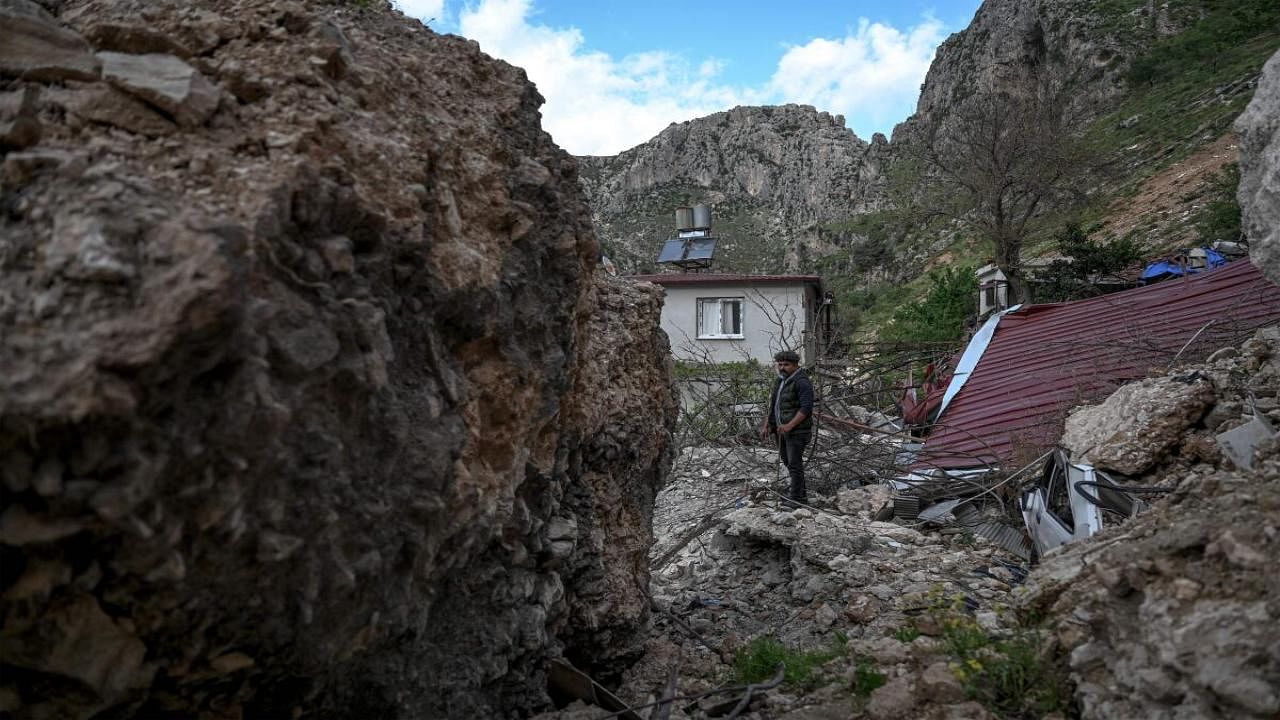 A 38-year-old security guard, stands next to buildings destroyed by fallen stones of the Staurin mountain, two months after a 7.8-magnitude jolt and its aftershocks wiped out swathes of Turkey's mountainous southeast, in Antakya. Credit: AFP Photo