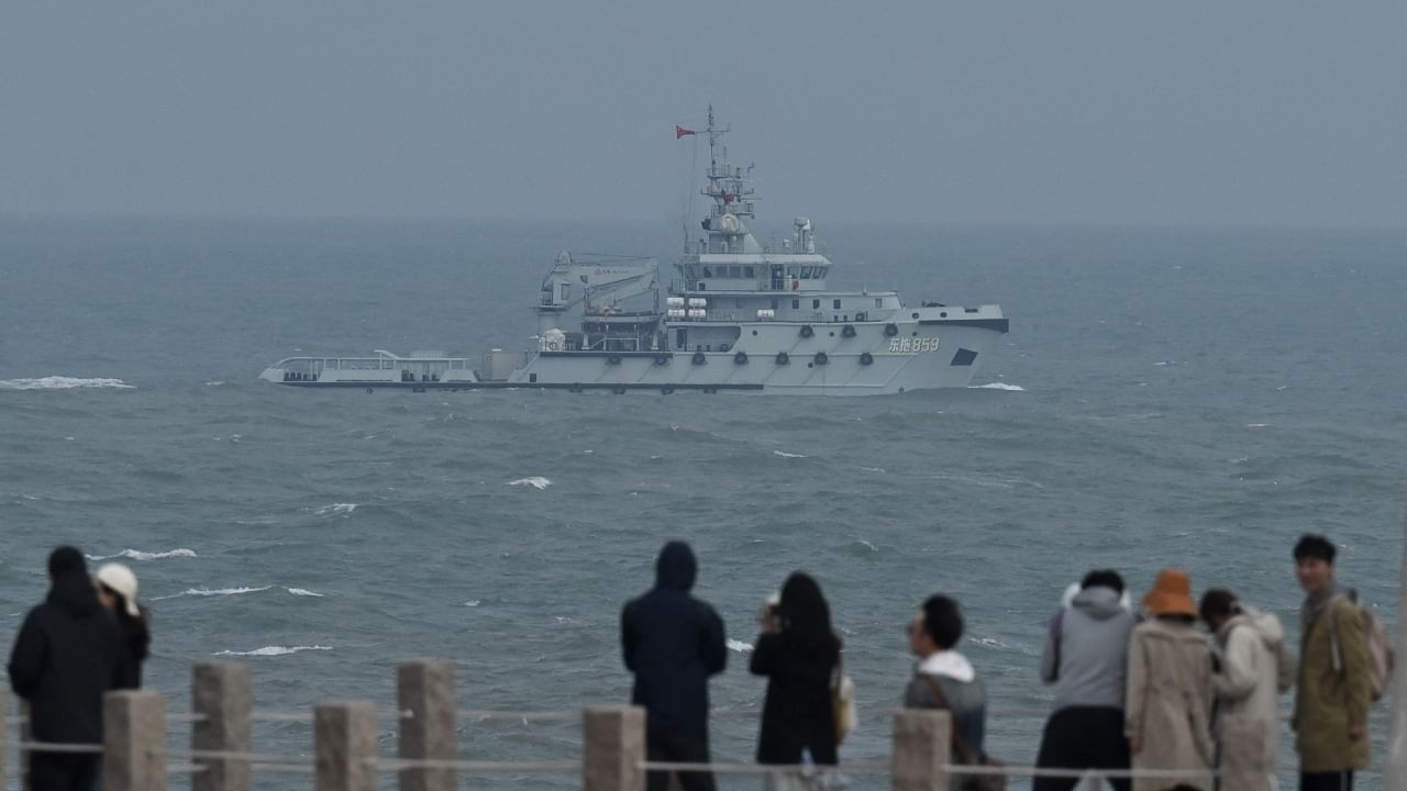 A PLA Navy tugboat sails in the Taiwan Strait, past tourists on Pingtan island, the closest point to Taiwan, in China's southeast Fujian province on April 7, 2023. Credit: AFP Photo