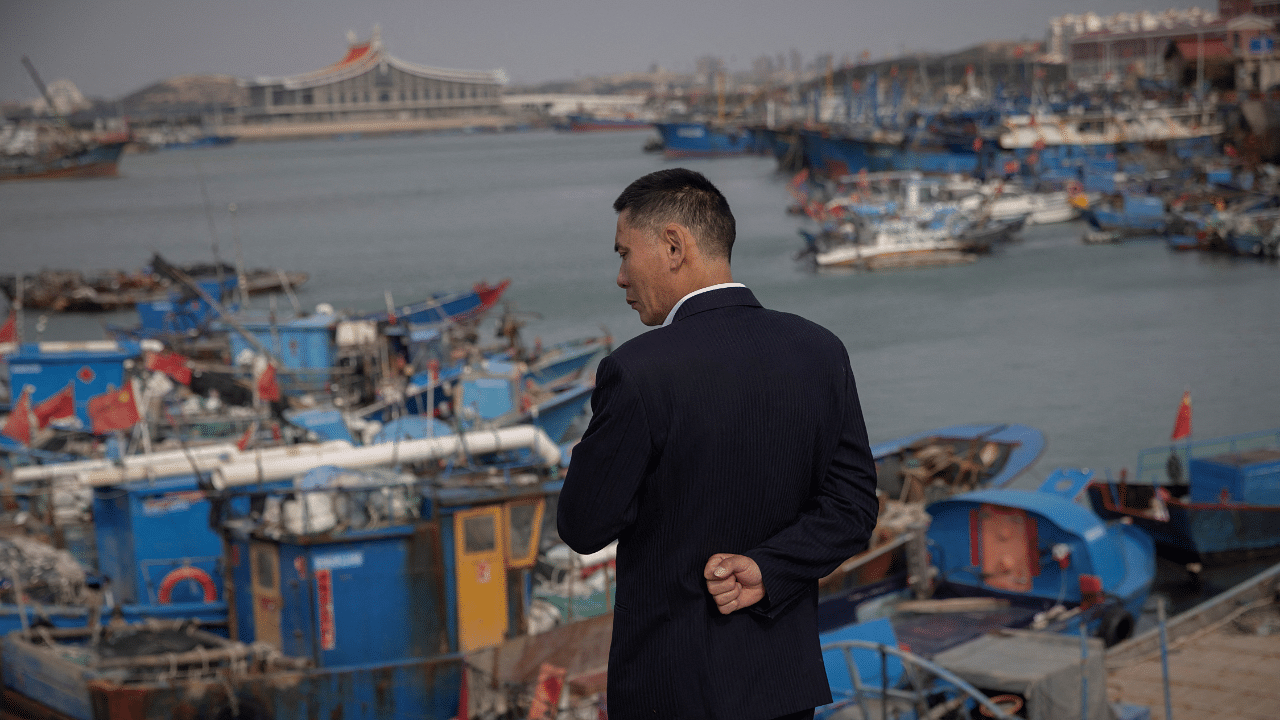 A man overlooks a harbour on Pingtan Island where fishing boats are moored that sail the Taiwan Strait, Fujian province, China. Credit: Reuters Photo