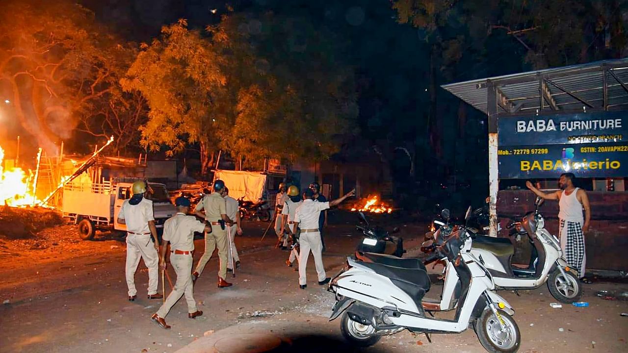 Police personnel at the fire incident site where several shops and vehicles reportedly set ablaze in a clash between two groups at Shastri Nagar area. Credit: PTI Photo