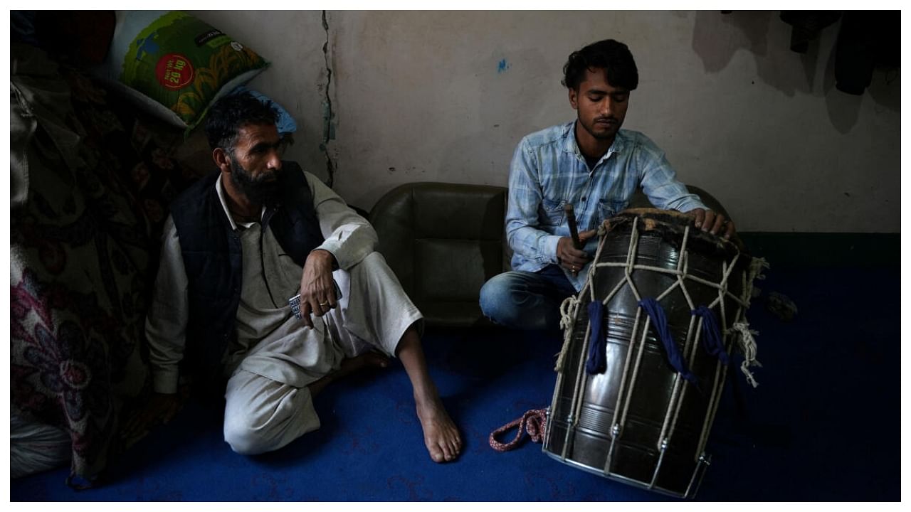 Arif Ahmad Jinded, 18, a Kashmiri Ramadan drummer locally known as 'Sahar Khan', fixes his drum that he uses to wake Muslims up for their meal before daybreak, next to his father Abdul Kareem Jinded. Credit: Reuters Photo