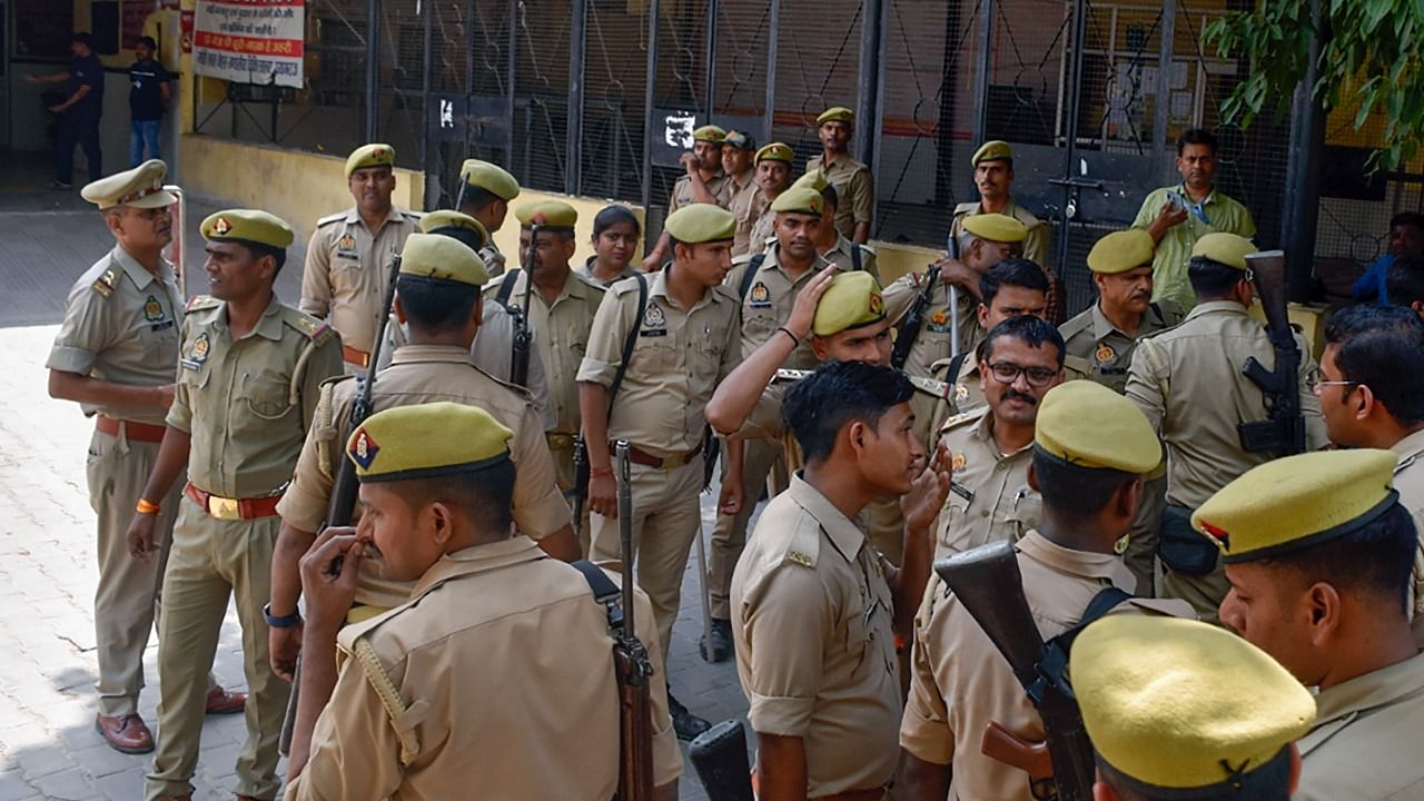 Police personnel stand guard as Special Investigation Team (SIT) and the forensic team investigate at the crime scene. Credit: PTI Photo