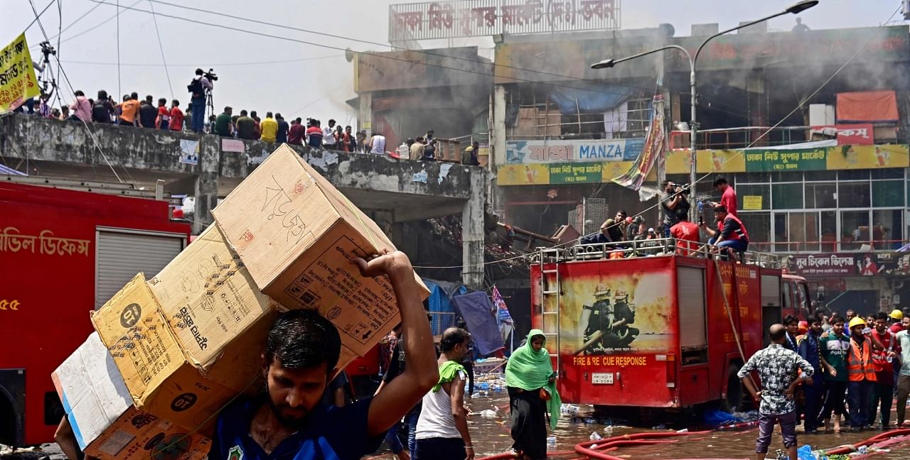A businessman carry goods after a fire broke out at a market in Dhaka on April 15, 2023. Credit: AFP Photo