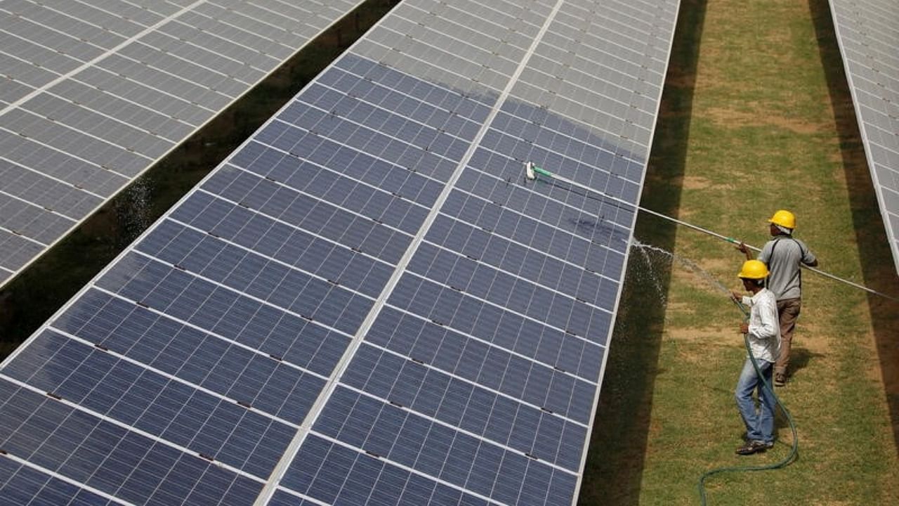 Workers clean photovoltaic panels inside a solar power plant in Gujarat, July 2015. Credit: Reuters File Photo