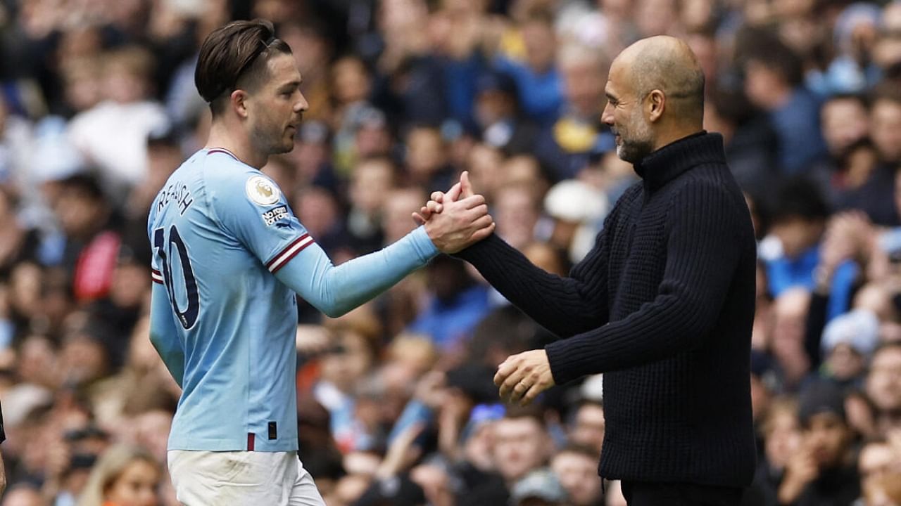 Manchester City's Jack Grealish shakes hands with manager Pep Guardiola. Credit: Reuters Photo