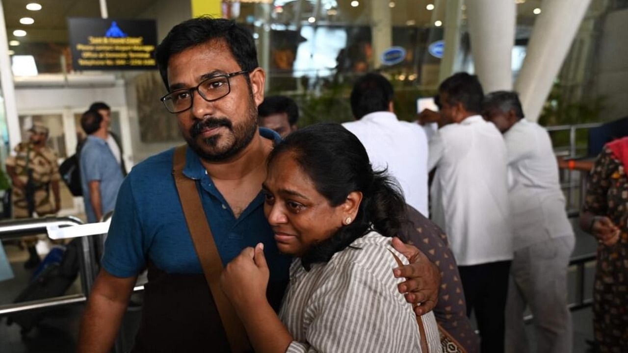 Indian nationals, who were stranded in Sudan, embrace as they exit the domestic terminal of the Chennai International Airport in Chennai on April 27, 2023, following her evacuation. Credit: AFP Photo