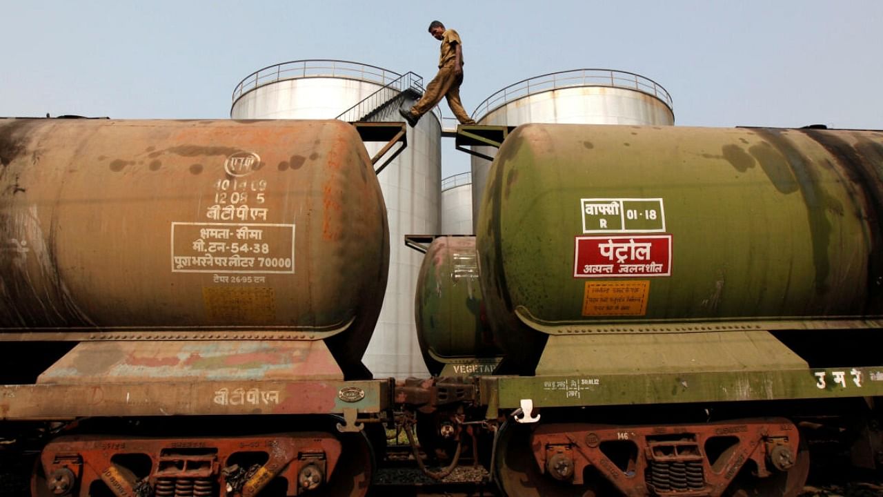 A worker walks atop a tanker wagon to check the freight level at an oil terminal. Credit: Reuters Photo