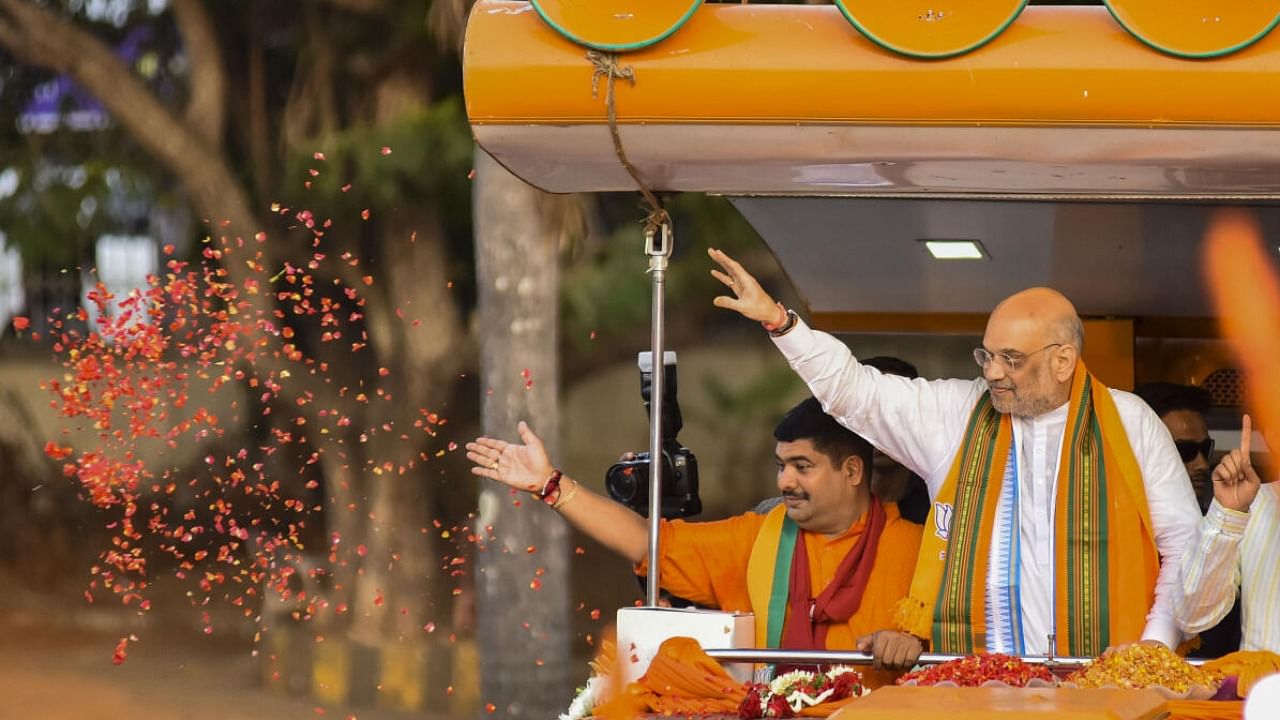 Amit Shah waves at supporters during a roadshow ahead of Assembly polls, in Mangaluru. Credit: PTI Photo