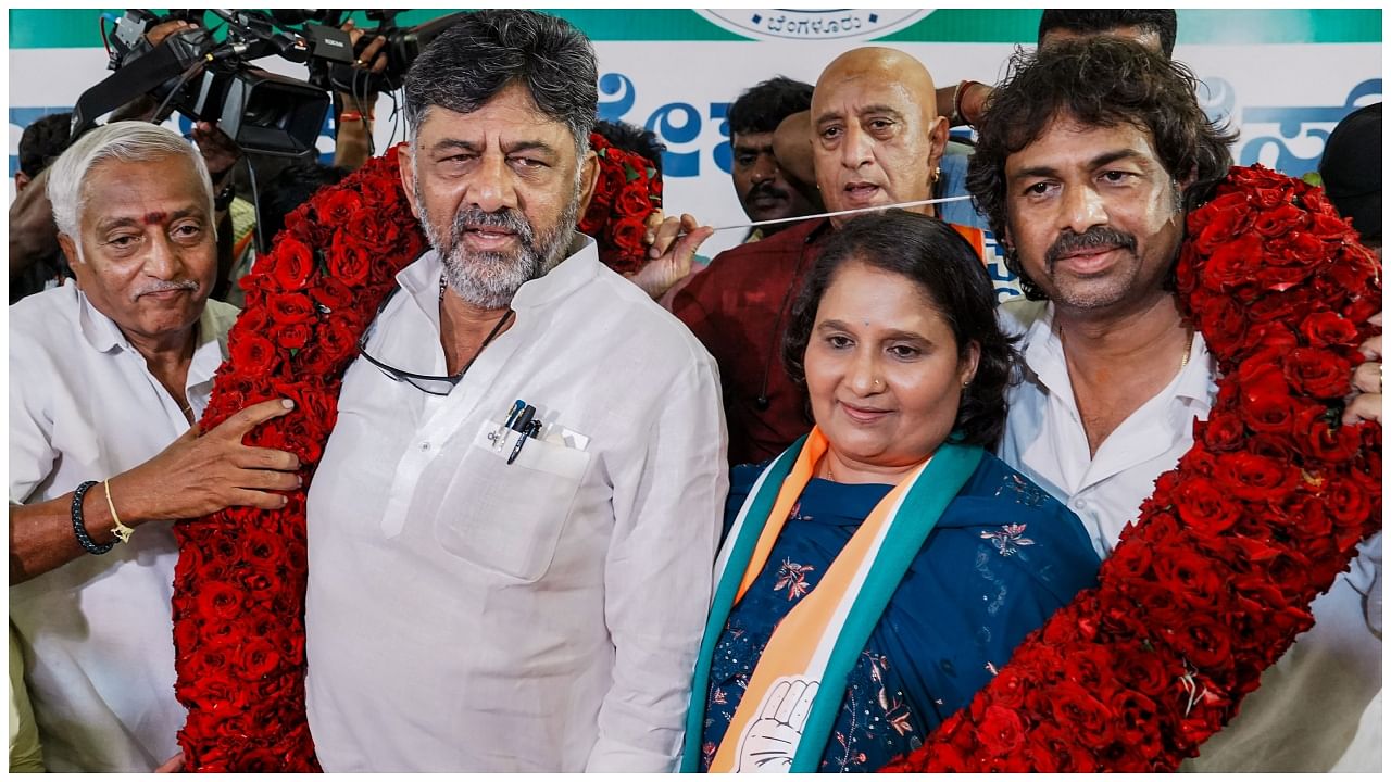 Karnataka Congress President D.K. Shivakumar with Geetha Shivarajkumar, wife of Kannada film actor Shivarajkumar, and party leader Madhu Bangarappa (R) being garlanded during a party joining programme. Credit: PTI Photo