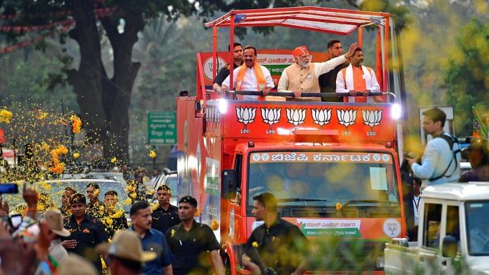 Prime Minister Narendra Modi waves at the crowd during his roadshow in Bengaluru on Saturday. Lok Sabha member Sadananda Gowda and MLC Narayanaswamy are seen. Credit: DH Photo/Ranju P