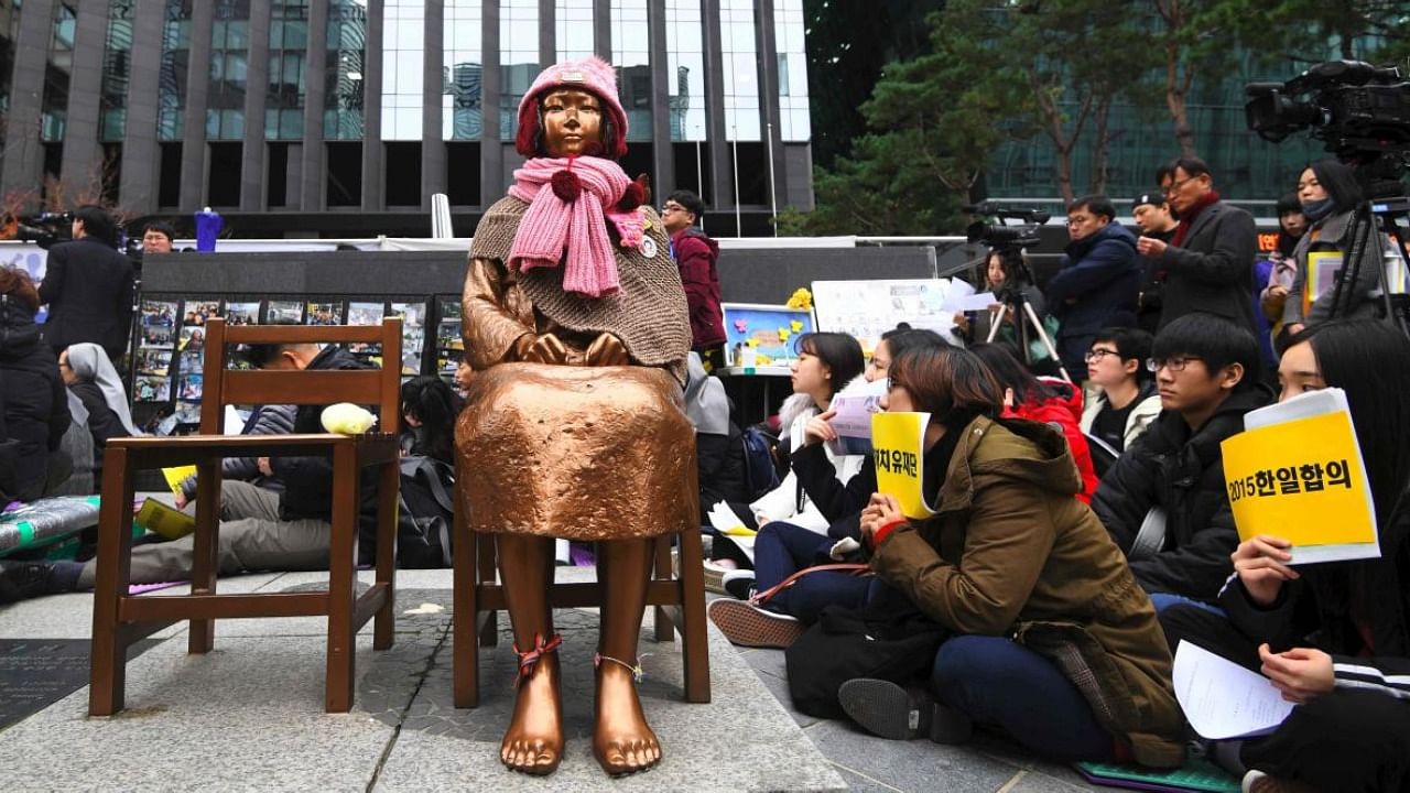 Protesters near a statue of a teenage girl symbolizing former 'comfort women', who served as sex slaves for Japanese soldiers during World War II. Credit: AFP Photo