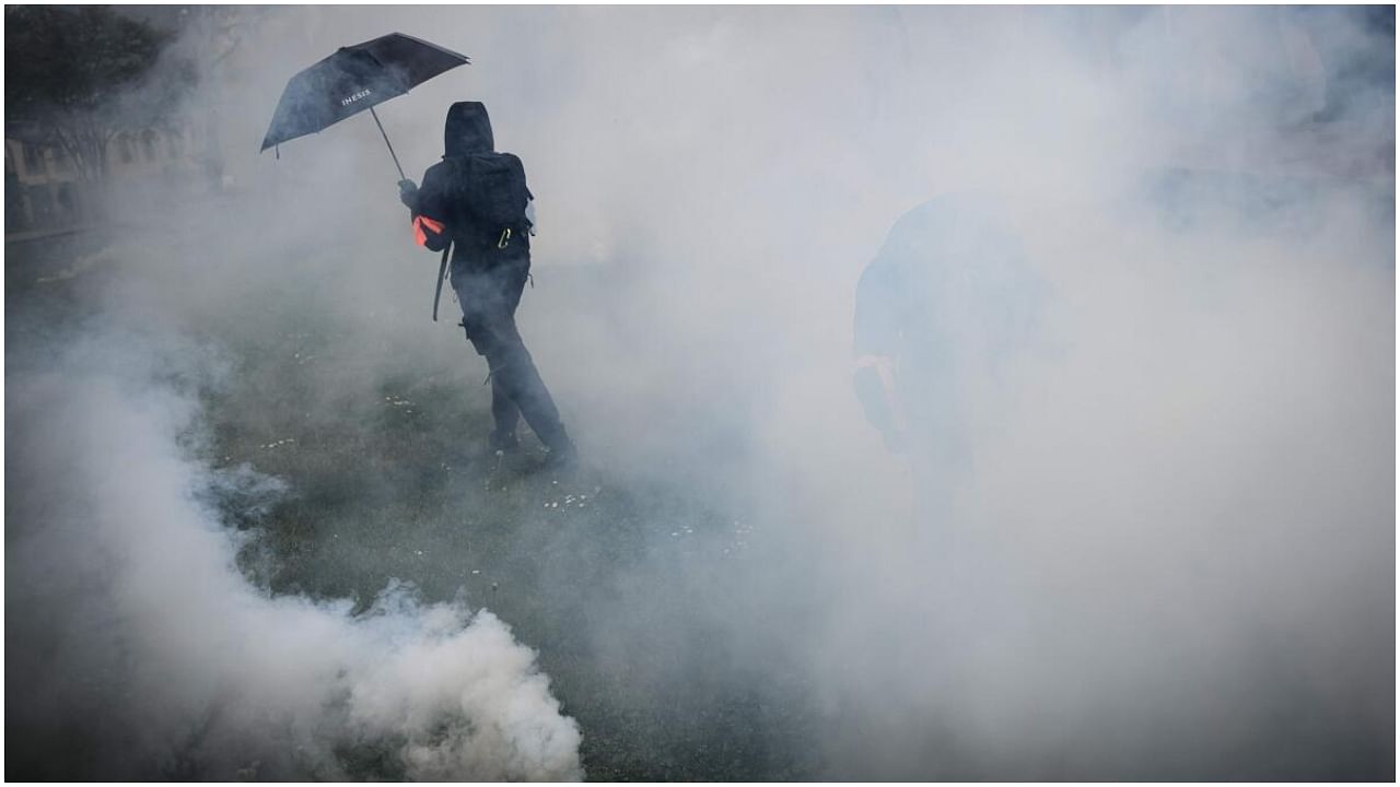 A protestor stands in clouds of tear gas amid clashes with riot police during a demonstration on May Day (Labour Day), to mark the international day of workers, more than a month after the government pushed an unpopular pensions reform act through parliament, in Nantes, northwestern France, on May 1, 2023. Credit: AFP Photo