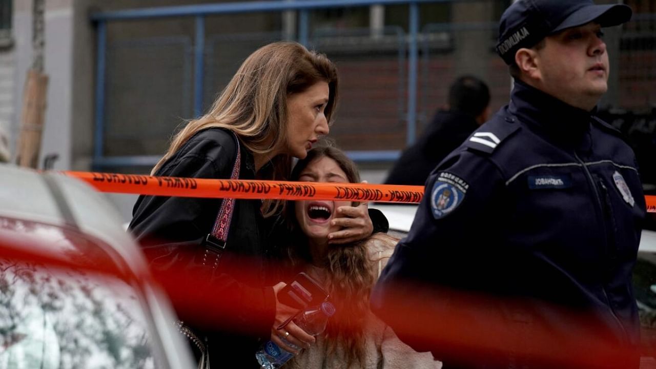 A parent escorts her child following a shooting at a school in the capital Belgrade. Credit: AFP Photo