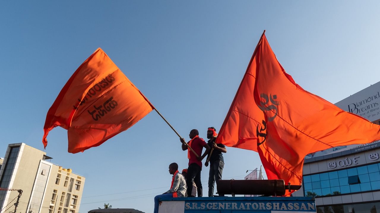 wo men waving saffron flags on top of a vehicle at a Hindutva rally in the city of Hassan. Credit: iStock Photo