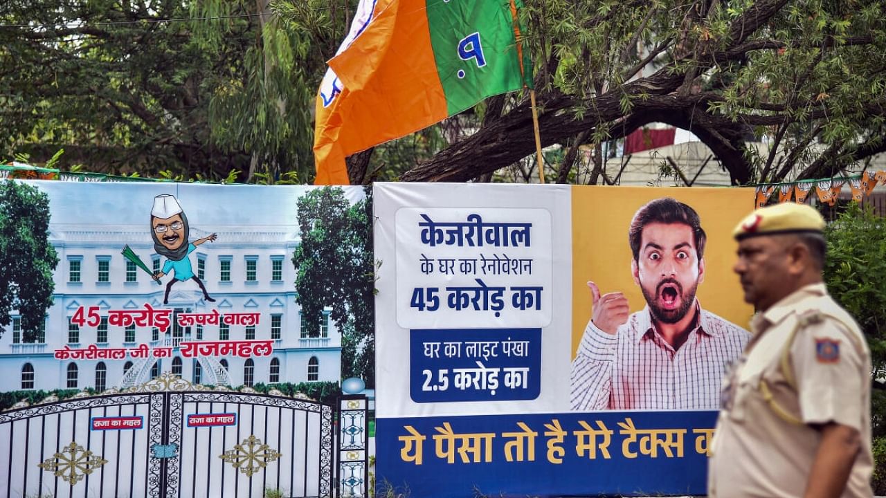 A police personnel walks past a billboard accusing Delhi Chief Minister Arvind Kejriwal of spending crores on the renovation of his official residence, in New Delhi, Tuesday, May 2, 2023. Credit: PTI Photo