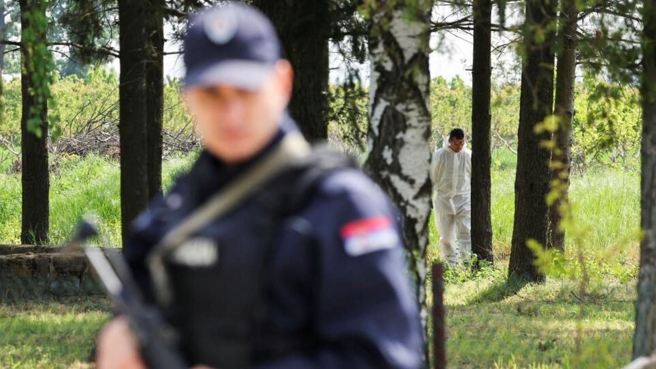 A member of the forensic team inspects the crime scene, in the aftermath of a shooting, in Malo Orasje, Serbia, May 5, 2023. Credit: Reuters Photo