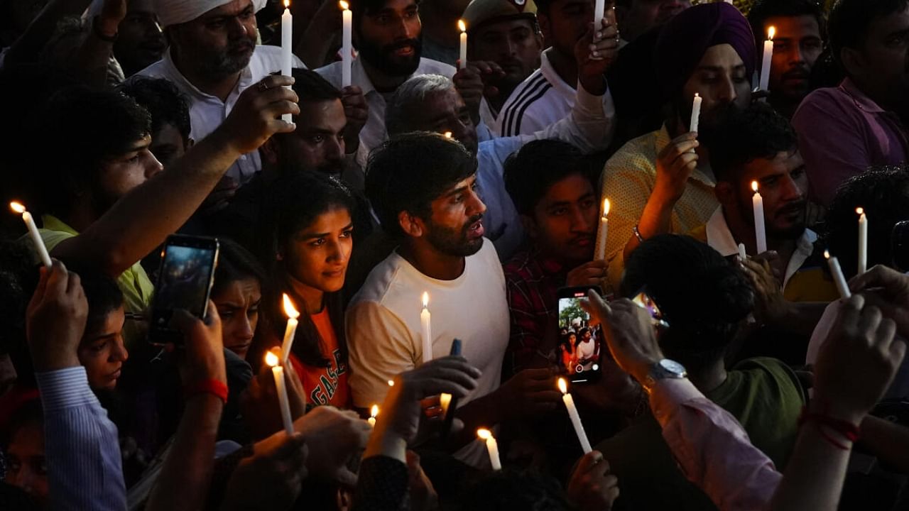 Wrestlers Sakshi Malik, Vinesh Phogat, Sangeeta Phogat and Bajrang Punia light candles during their protest at Jantar Mantar, in New Delhi. Credit: PTI Photo