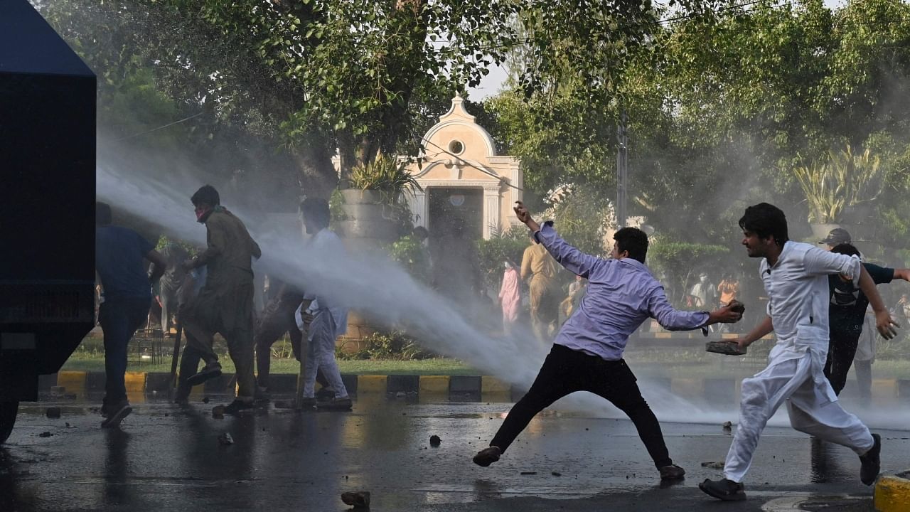 Pakistan Tehreek-e-Insaf (PTI) party activists and supporters of former Pakistan's Prime Minister Imran throw stones to a police water cannon vehicle during a protest against the arrest of their leader, in Lahore on May 9, 2023. Credit: AFP Photo