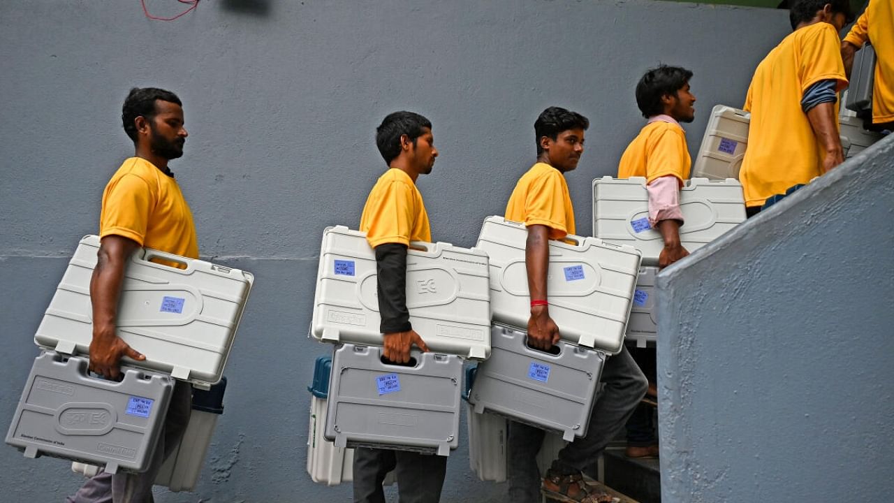 Volunteers carry election material at a mustering centre in Rajarajeshwari Nagar on Tuesday. Credit: DH Photo/Pushkar V