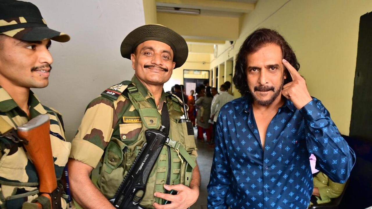 Actor Upendra with security guards outside a polling booth in Basavanagudi on Wednesday. DH PHOTO/Kishor Kumar Bolar