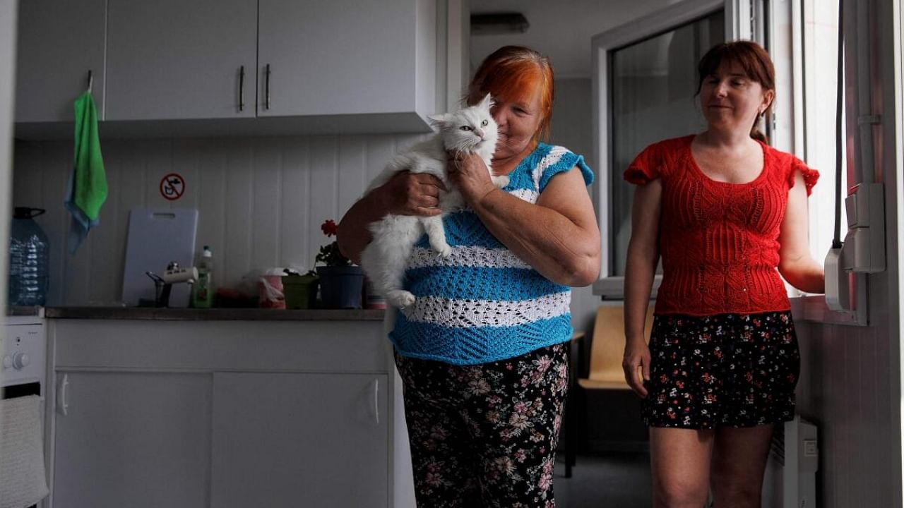 In this file photo taken on August 08, 2022, refugee 66 years old Anna Gallum (L) holds her cat as her daughter Swetlana Gallum (45yo) from Odessa stand in the kitchen of their container-accommodation at the former Tempelhof Airport in Berlin, Germany. Credit: AFP Photo