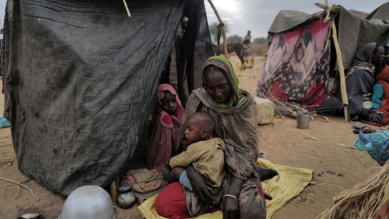 Mekka, 30, a Sudanese refugee who has fled the violence in Sudan's Darfur region, sits with her children beside their makeshift shelter near the border between Sudan and Chad in Koufroun, Chad May 11, 2023. Credit: Reuters Photo