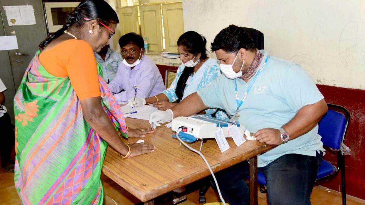 Polling official administers indelible ink to a voter, at a polling booth in Bengaluru. Credit: IANS Photo