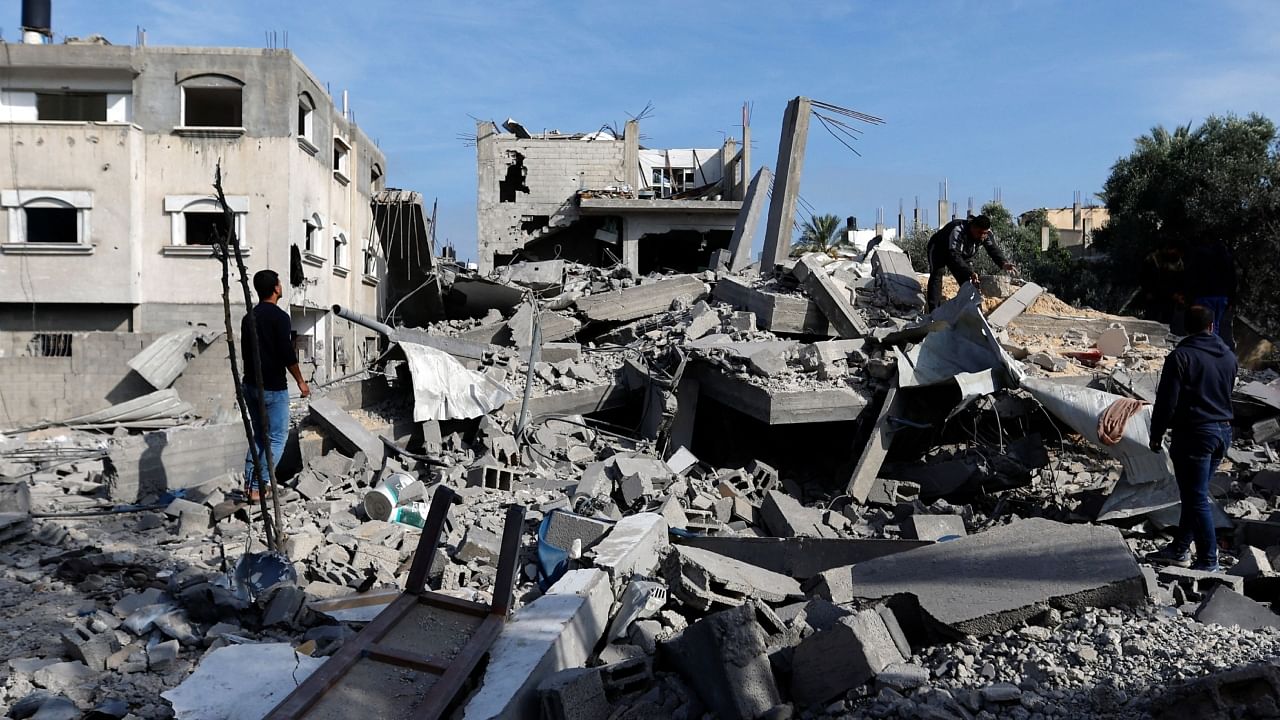 Palestinians stand among the rubble of buildings, which were damaged in an Israeli strike during Israel-Gaza fighting. Credit: Reuters Photo