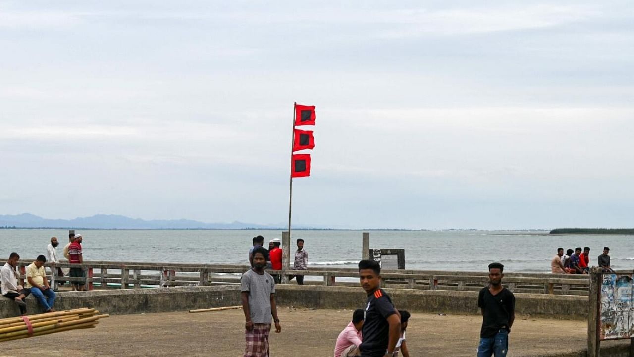 People gather beside a storm danger signal flag in Shahpori island jetty in Bangladesh. Credit: AFP 