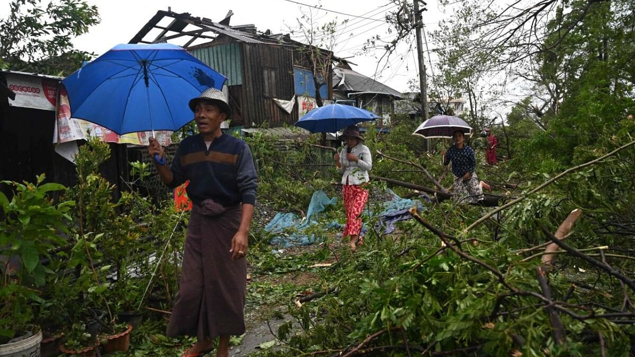 Myanmar locals walk past destruction left in the wake of Cyclone Mocha. Credit: AFP Photo