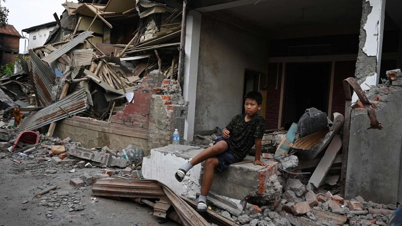 A boy sits on top of the rubbles of a house that was set on fire and vandalised by mobs in Khumujamba village, on the outskirts of Churachandpur in violence-hit northeastern Indian state of Manipur, on May 9, 2023. Credit: AFP Photo