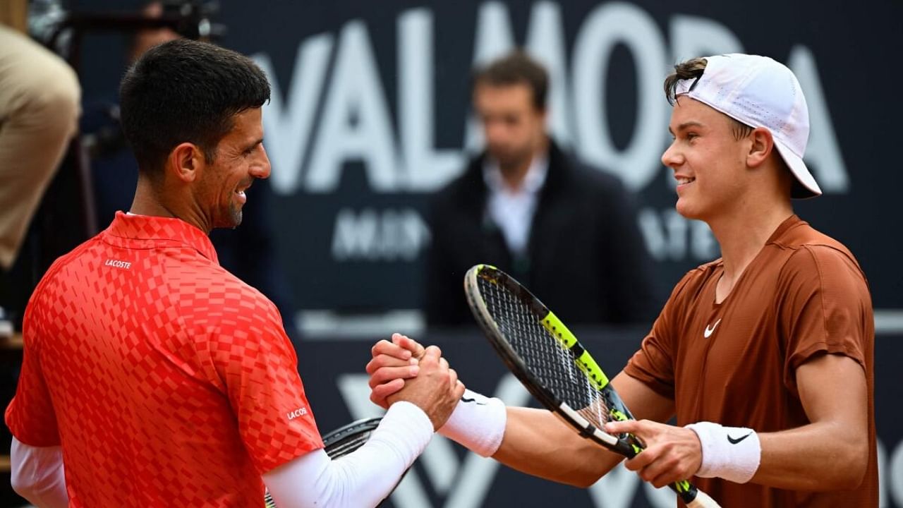 Denmark's Holger Rune (R) and Serbia's Novak Djokovic shake hands after Rune won their quarterfinals match of the Men's ATP Rome Open tennis tournament at Foro Italico in Rome. Credit: AFP Photo