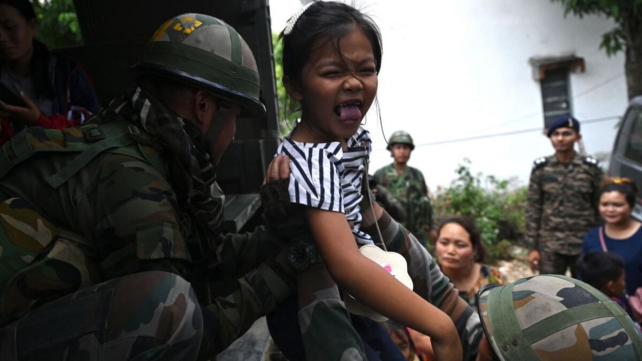 Indian Army personnel helps a girl in violence hit Manipur. Credit: AFP Photo