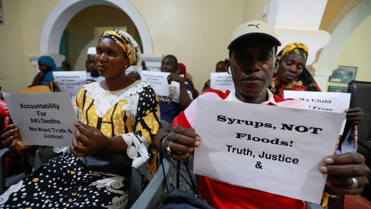 Grieving parents hold up signs during a news conference, calling for justice for the deaths of children linked to contaminated Indian cough syrups, in Serekunda, Gambia, November 4, 2022. Credit: Reuters File Photo