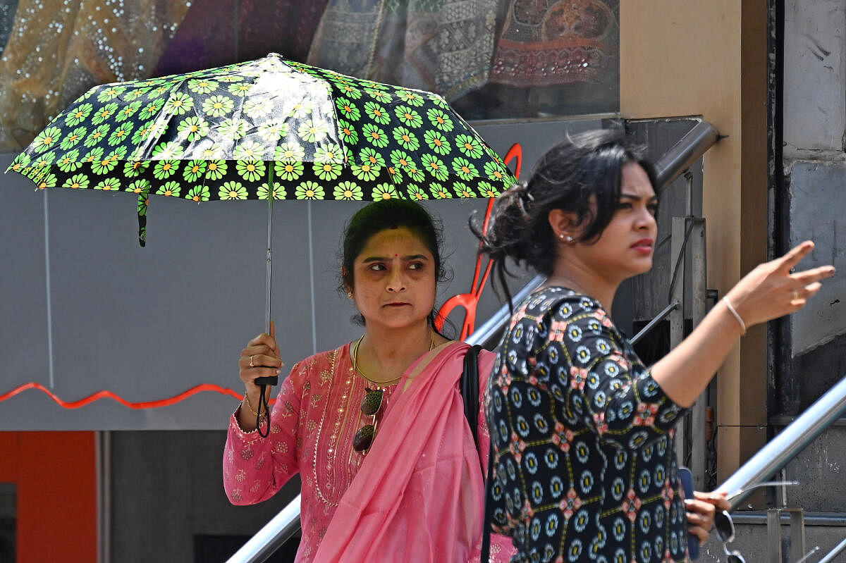 People take cover under an umbrella on a hot day in Bengaluru. Credit: DH File Photo/Pushkar V