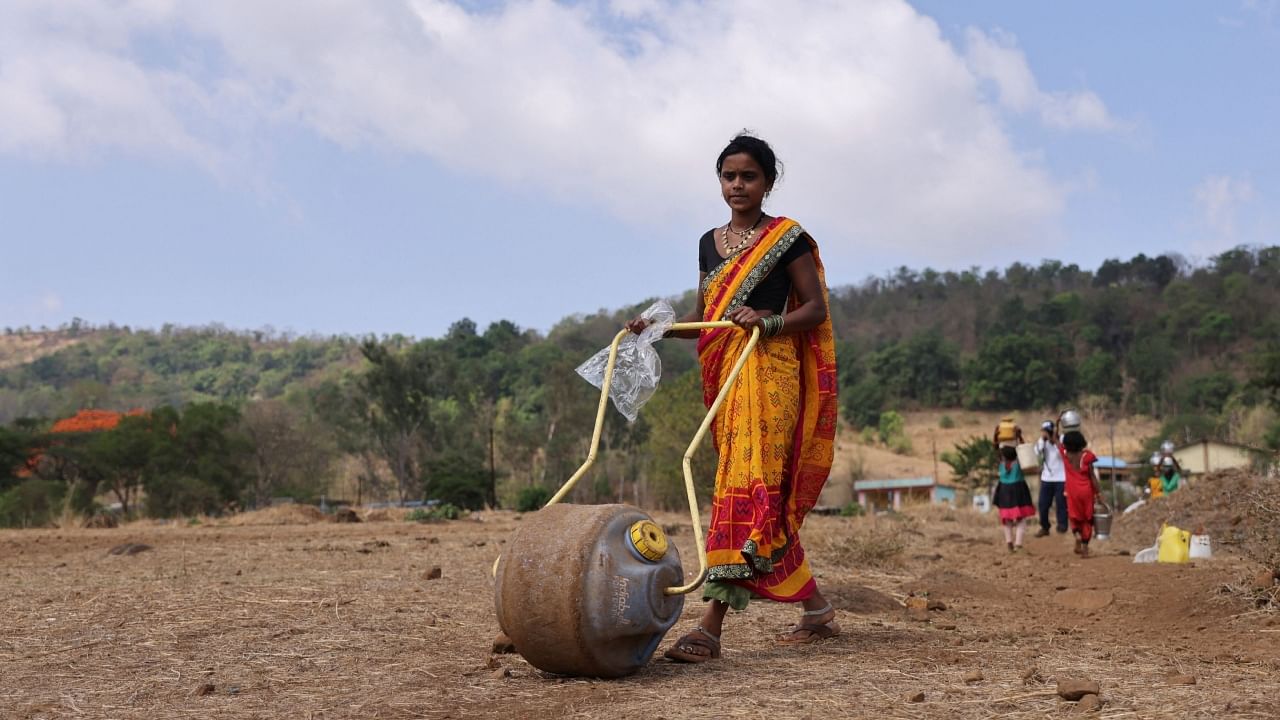 A woman pushes a water roller tank towards a well to collect water in Telamwadi, near Mumbai, India, May 16, 2023. Credit: Reuters Photo