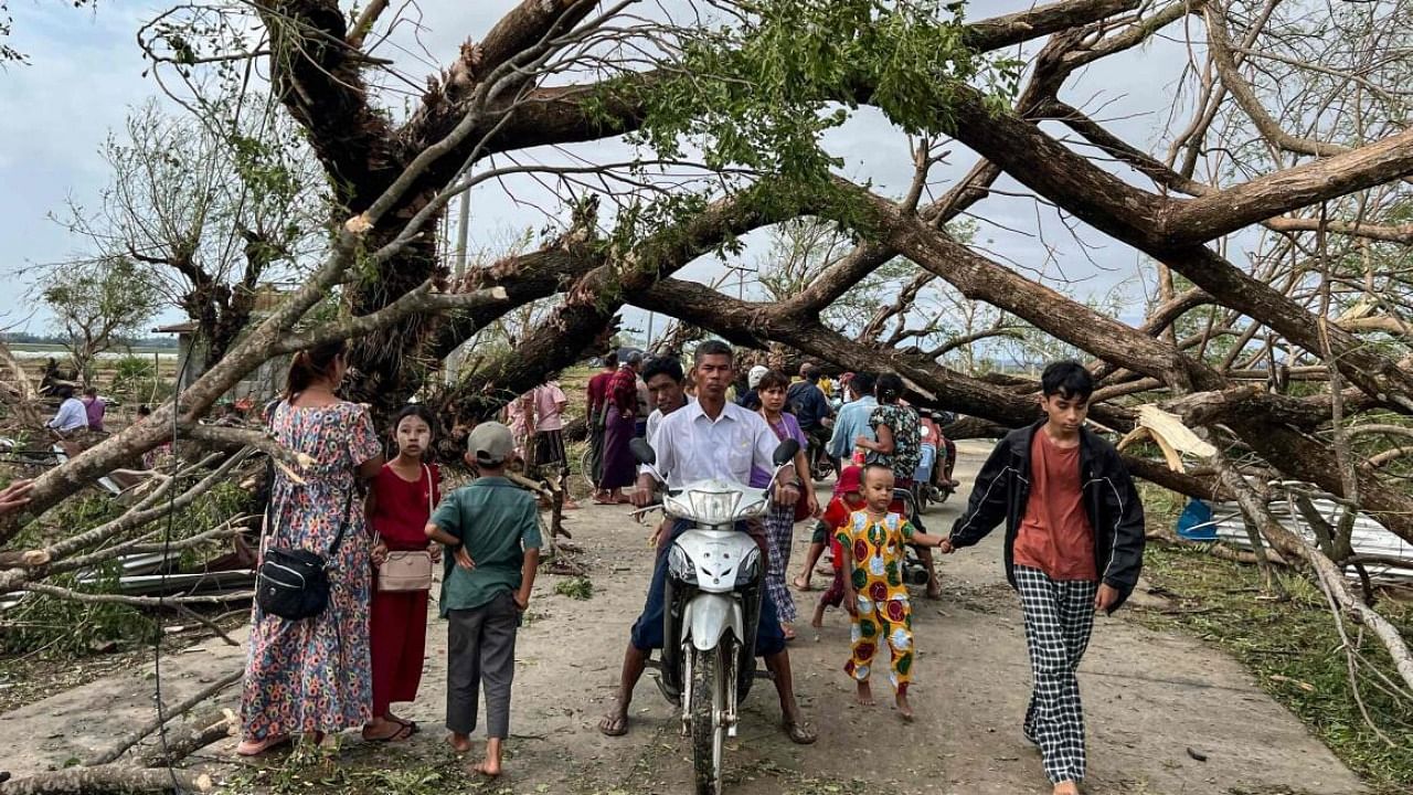 Residents walk past fallen trees in Kyauktaw in Myanmar's Rakhine state after Cyclone Mocha crashed ashore. Credit: AFP File Photo